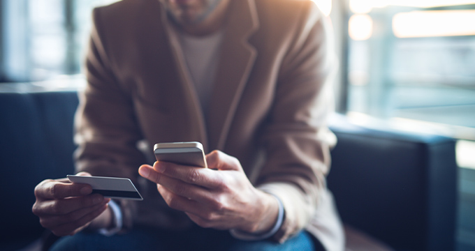 A person holding their phone and their credit card