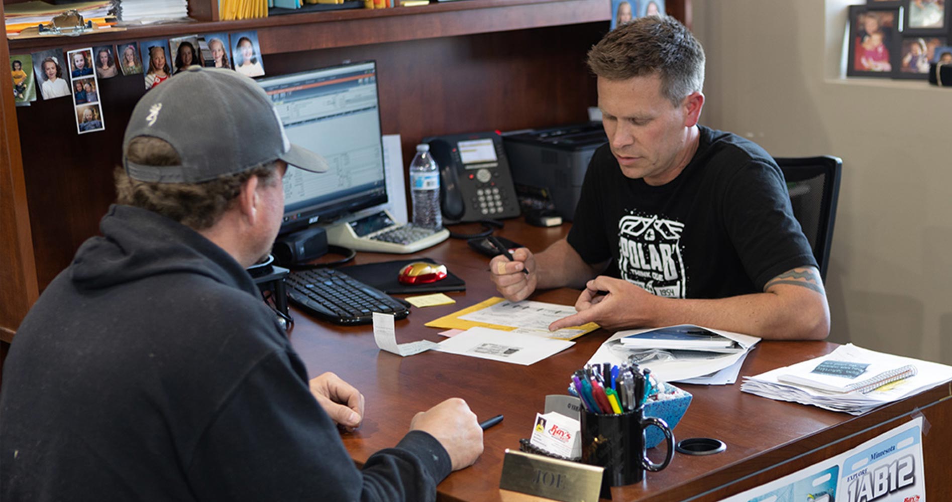 A salesperson sitting at his desk with a customer