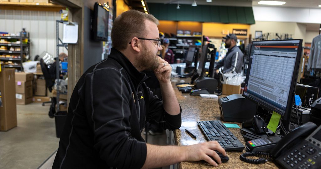 A man looking at a computer monitor behind a service desk