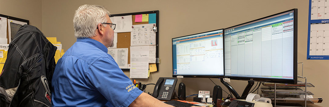 A man sitting at a desk in front of two computer monitors